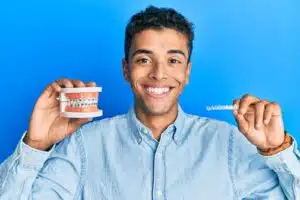 Adult holding dental model and clear aligner comparing braces or aligners for adults